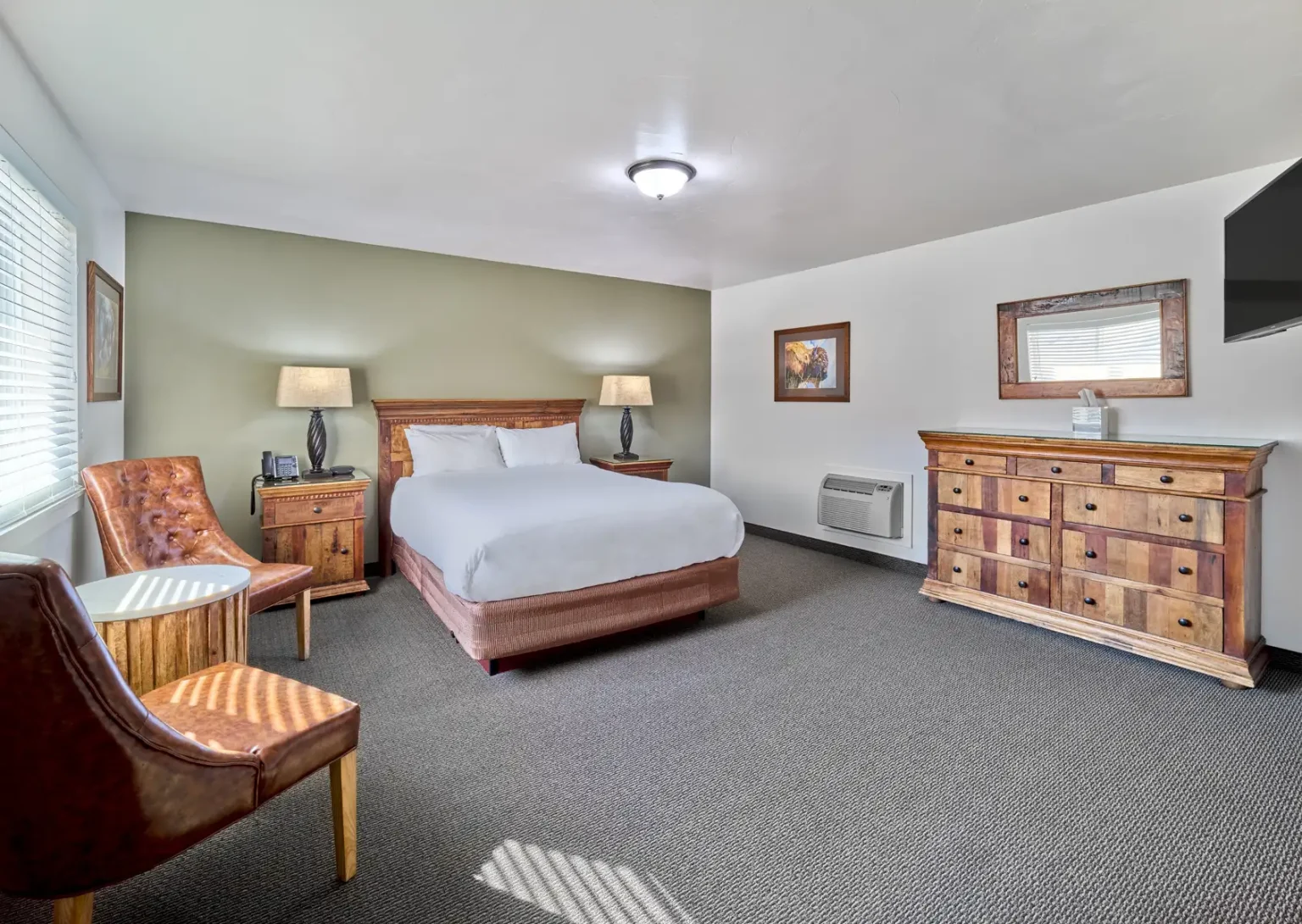 A hotel room with a bed, dresser, chair, and TV.