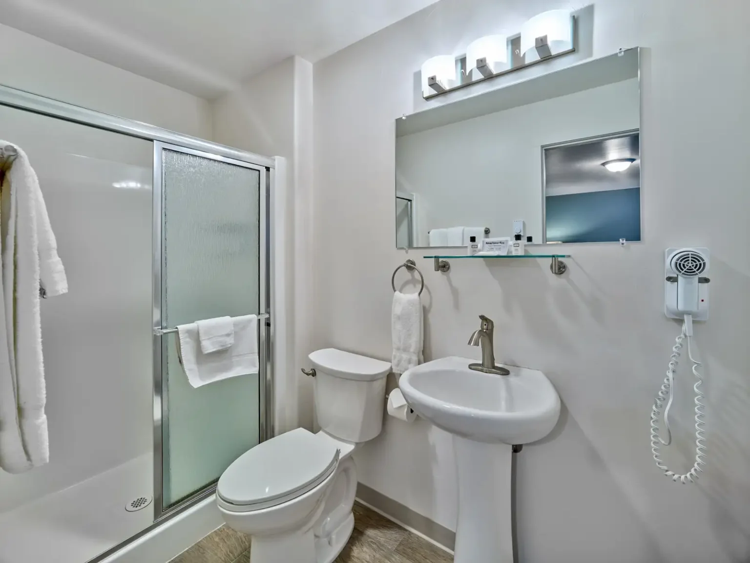 A clean bathroom with a toilet, shower, sink, and mirror.